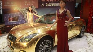 Models pose with a gold-plated Infiniti