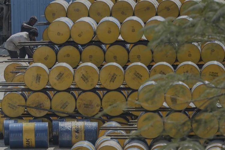 A worker stacks oil barrels at a filling station in n Chennai on February 24, 2022. (Photo by Arun SANKAR / AFP)