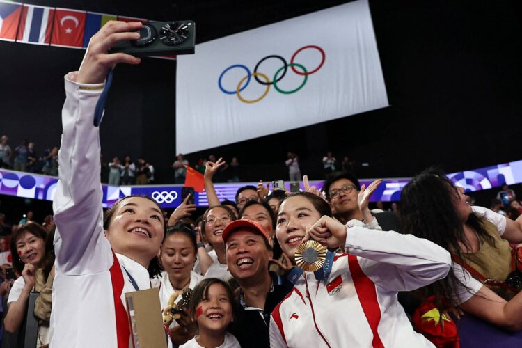 Paris 2024 Olympics - Badminton - Women's Doubles Victory Ceremony - Porte de La Chapelle Arena, Paris, France - August 03, 2024. Gold medallists Qing Chen Chen of China and Yi Fan Jia of China take a selfie with members of the audience during the ceremony. REUTERS/Ann Wang     TPX IMAGES OF THE DAY